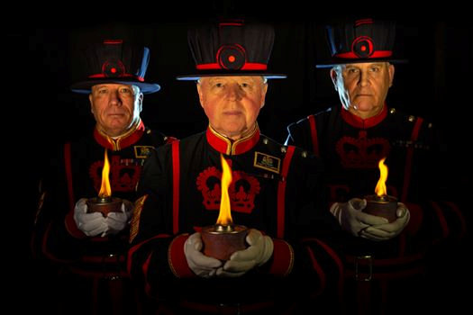 Three Beafeaters lighting torches and keeping vigil
