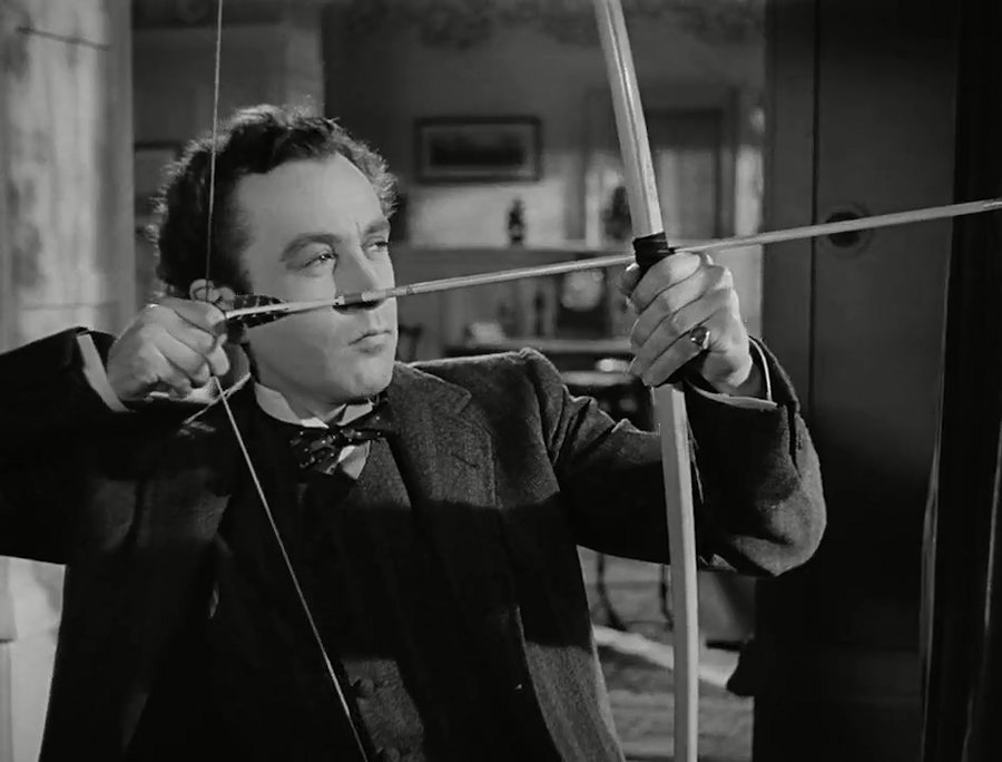 Dennis Price shooting a bow and arrow