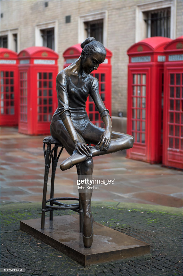 Ballerina Statue amidst a background of Telephone Kiosks
