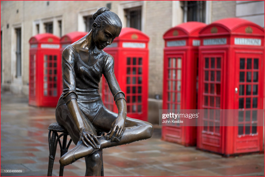 Ballerina Statue amidst a background of Telephone Kiosks